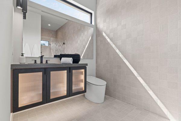 Zbranek Holt LakeLBJ Modern Luxury Lakehouse Bathroom GlassVanityLighting NaturalTile AngledSunlight