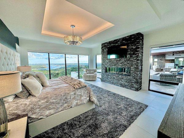 Modern Luxury Hill Top Master Bedroom Stone Fireplace Lake Travis View Floor to Ceiling Windows Zbranek and Holt Custom Homes