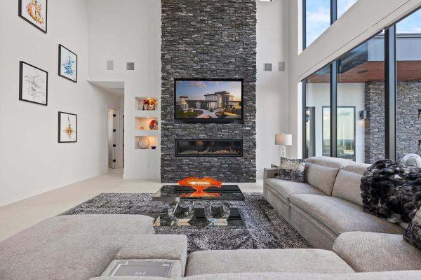 Modern Luxury Hill Top living room stacked stone fireplace built in shelves gray sectional Zbranek and Holt Custom Homes