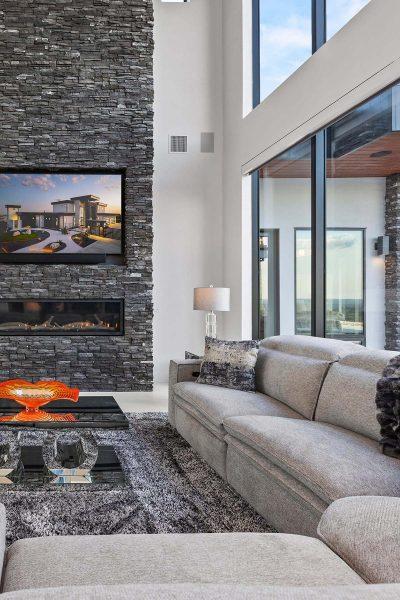 Modern Luxury Hill Top living room stone fireplace gray sectional glass walls Zbranek and Holt Custom Homes